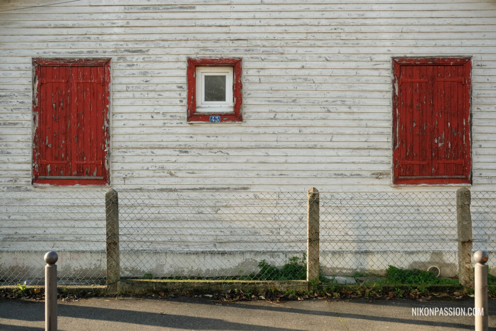Cadrage et composition en photo : Trois fenêtres attirent l'attention sur cette ancienne façade de maison en bois