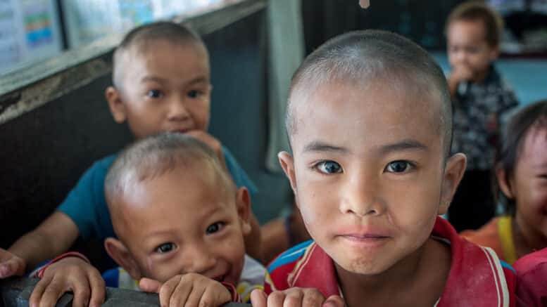 Portrait d’un enfant dans un village thaïlandais, pris au 35 mm en toute spontanéité, à travers une cloison d’école