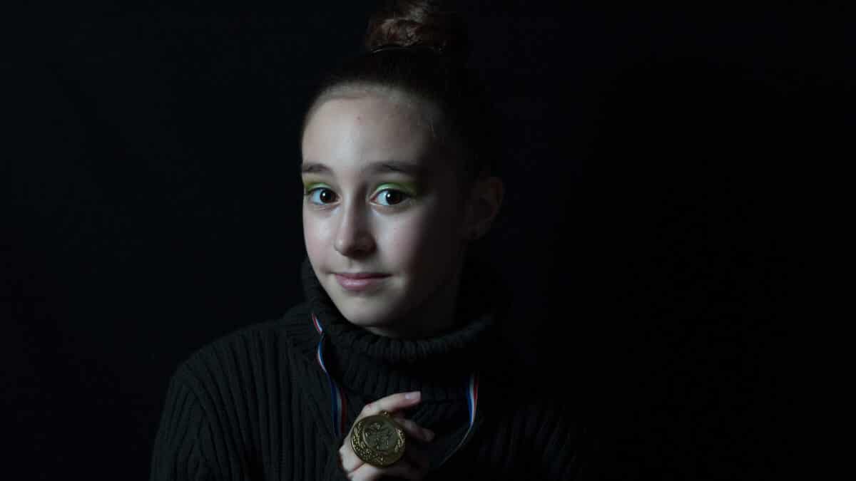 Portrait d'une jeune fille tenant une médaille à la main, en studio