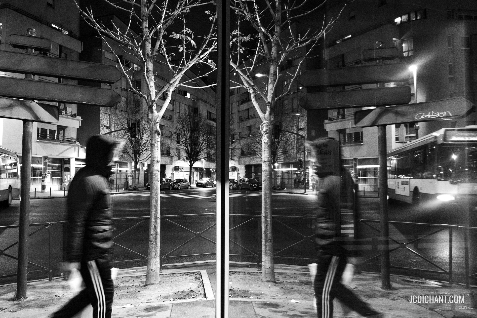 Un passant dans une rue de Vitry-sur-Seine de nuit avec reflet dans une vitrine - photo Jean-Christophe DICHANT