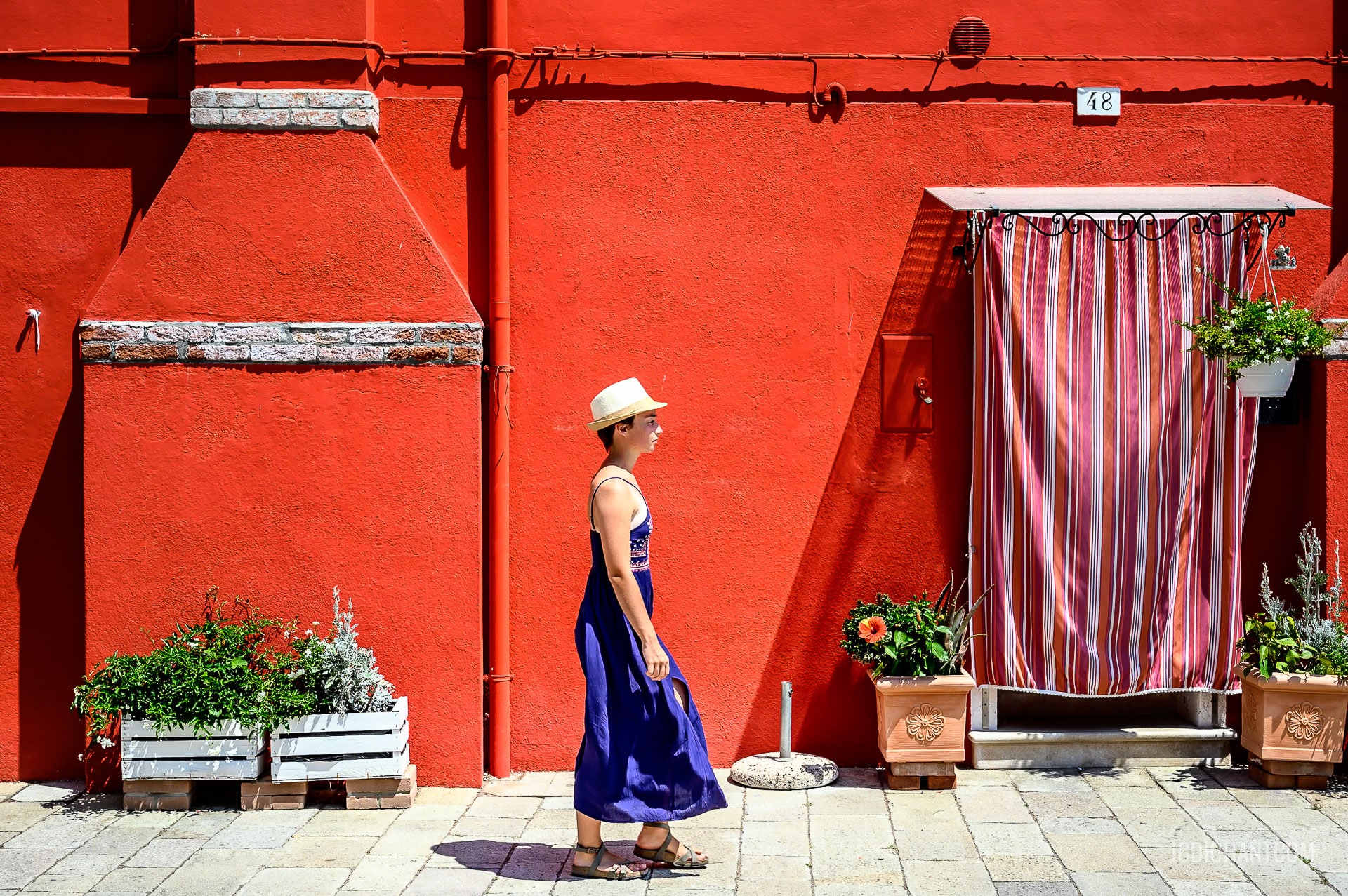 Une femme avec une robe bleue devant un mur rouge à Venise - photo (C) JC Dichant